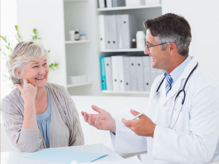 Smiling senior female patient in friendly consultation with male doctor at clinic