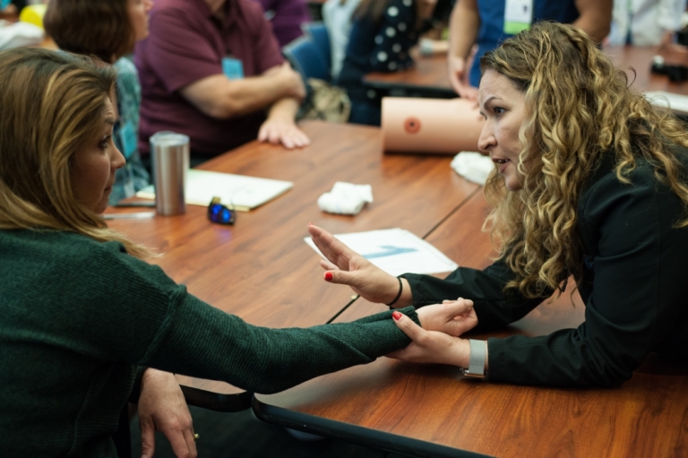 Instructor demonstrating wound care technique on participant's arm during Stop the Bleed training class