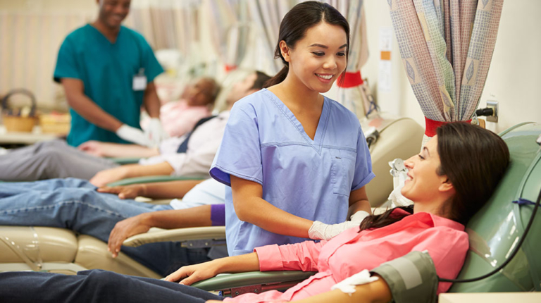 Nurse assisting smiling patient at blood donation center