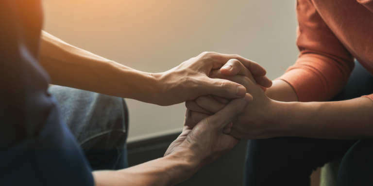 Two people holding hands in supportive gesture