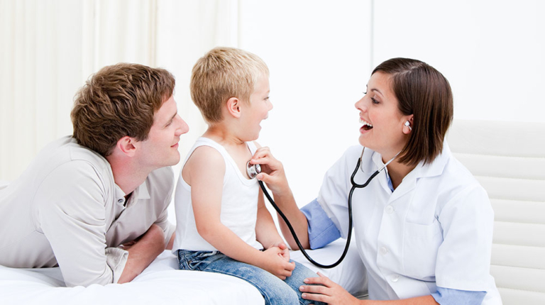 Doctor examining boy's chest with father present