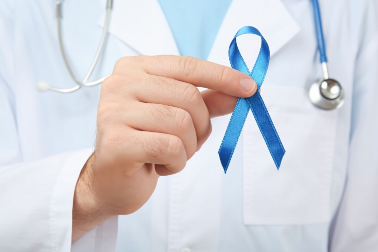 Doctor in white coat holding a blue awareness ribbon