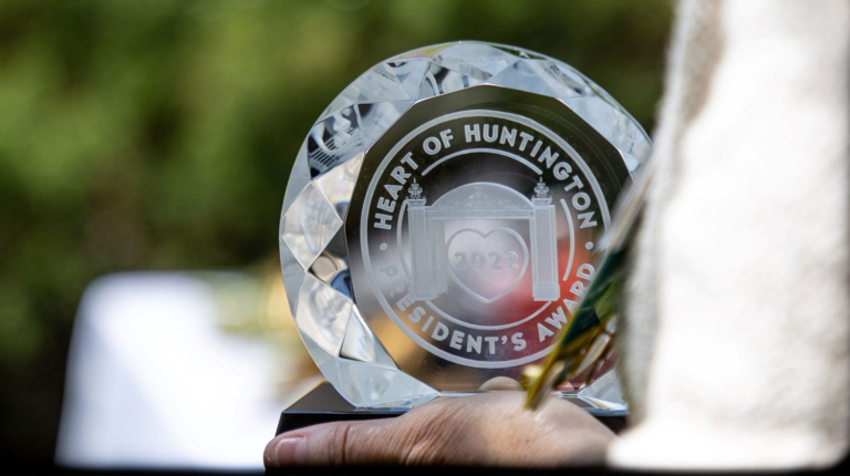 A person holding a glass award that says, "Heart of Huntington - President's Award"