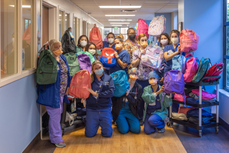 Hospital staff holding donated backpacks for Operation Backpack drive