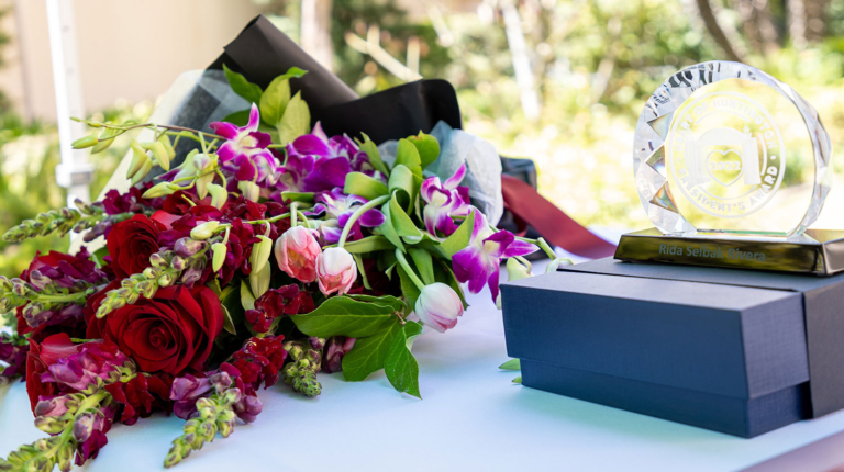 Bouquet of flowers laying on a table next to a Heart of Huntington award