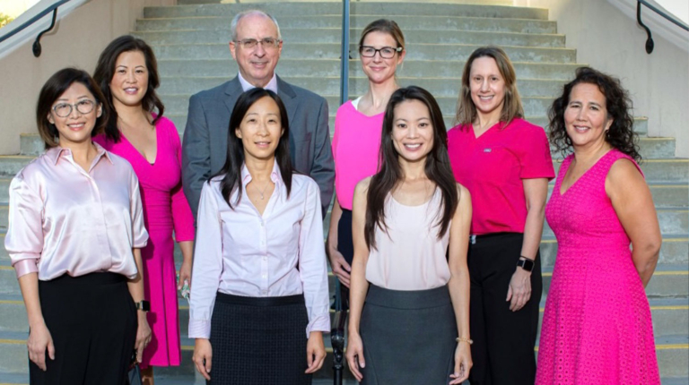 Group of eight oncology specialists and surgeons standing together