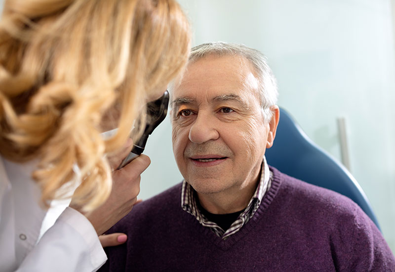 Ophthalmologist checking senior man's eyes with device