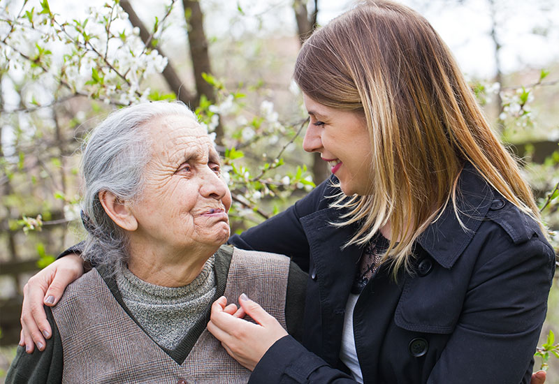 The Alzheimer's Los Angeles Memory Club: Thirty-something year old woman smiling at a senior woman with her arm around her shoulder
