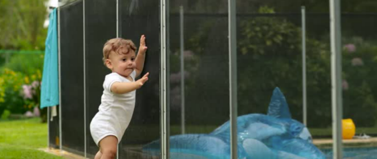 Baby stopped by pool safety fence barrier in backyard