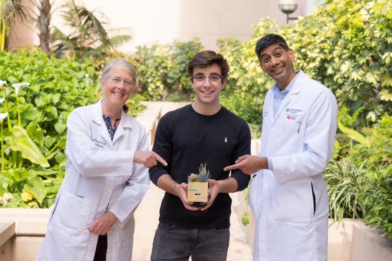 Two Huntington Health doctors posing with smiling patient in hospital courtyard